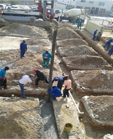 Workers placing concrete in foundation trenches